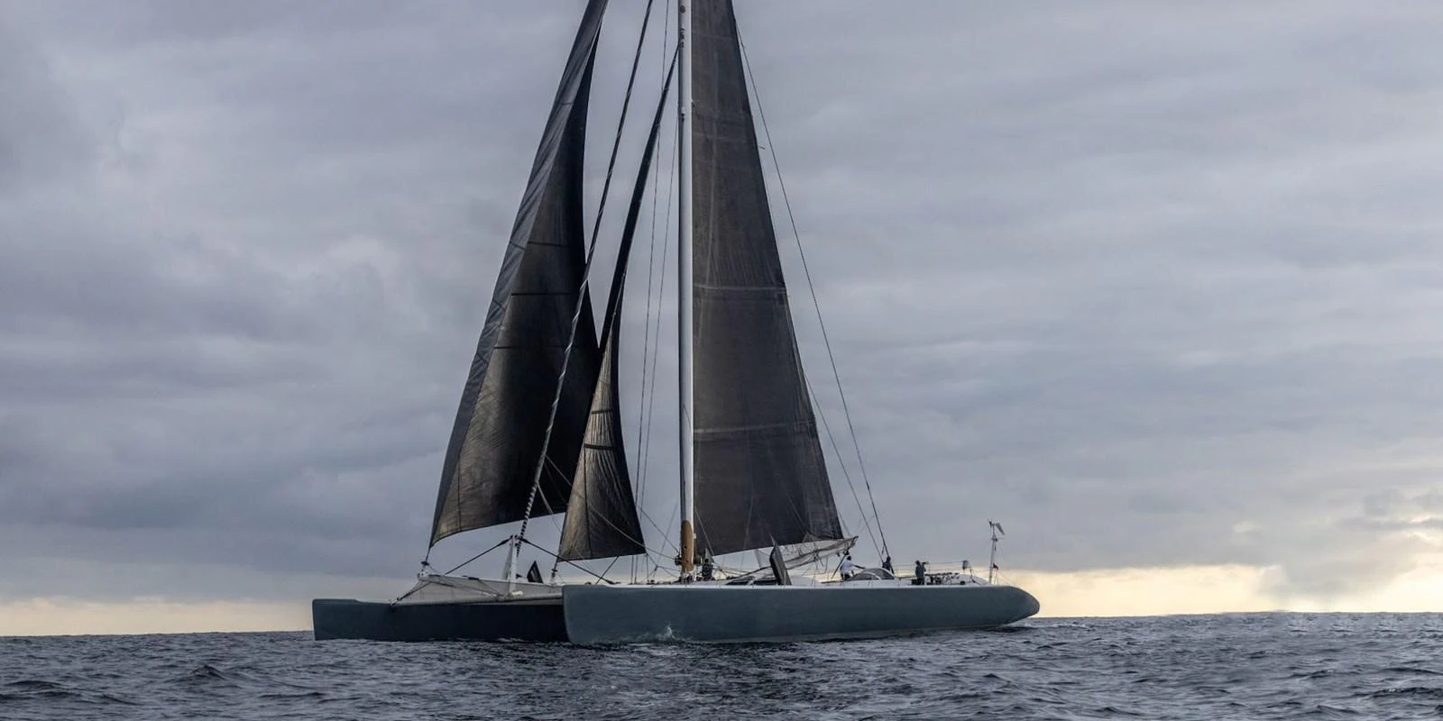 A sleek sailing yacht glides gracefully on the open water under a cloudy sky. aboard MAXICAT VICTORIA Yacht for Sale