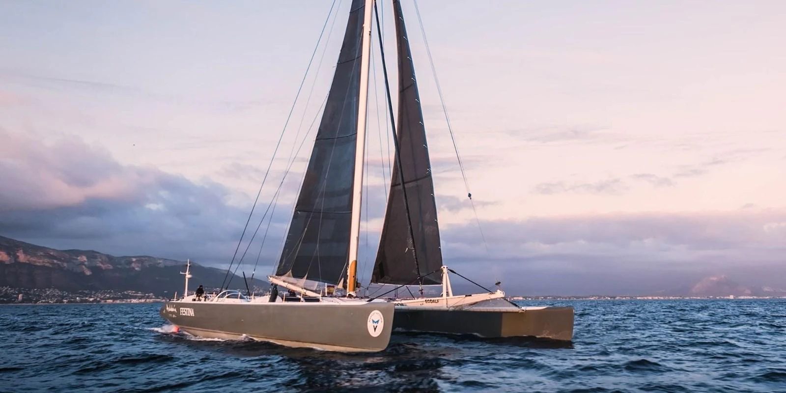 A sleek sailing yacht glides gracefully on the open water at sunset. aboard MAXICAT VICTORIA Yacht for Sale