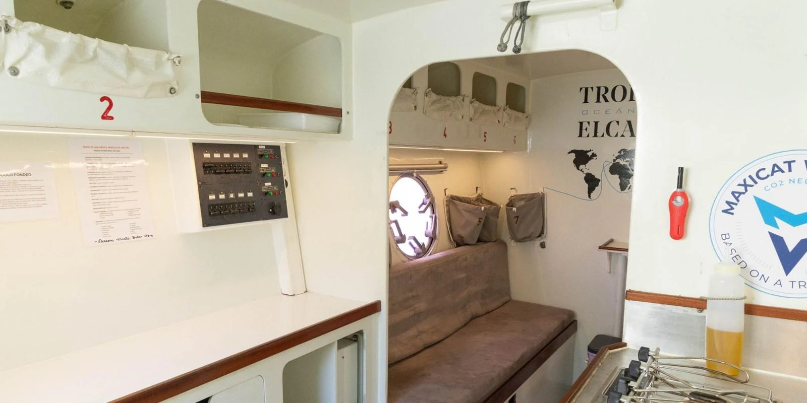The yacht's interior features a cozy seating area with a porthole and functional amenities. aboard MAXICAT VICTORIA Yacht for Sale