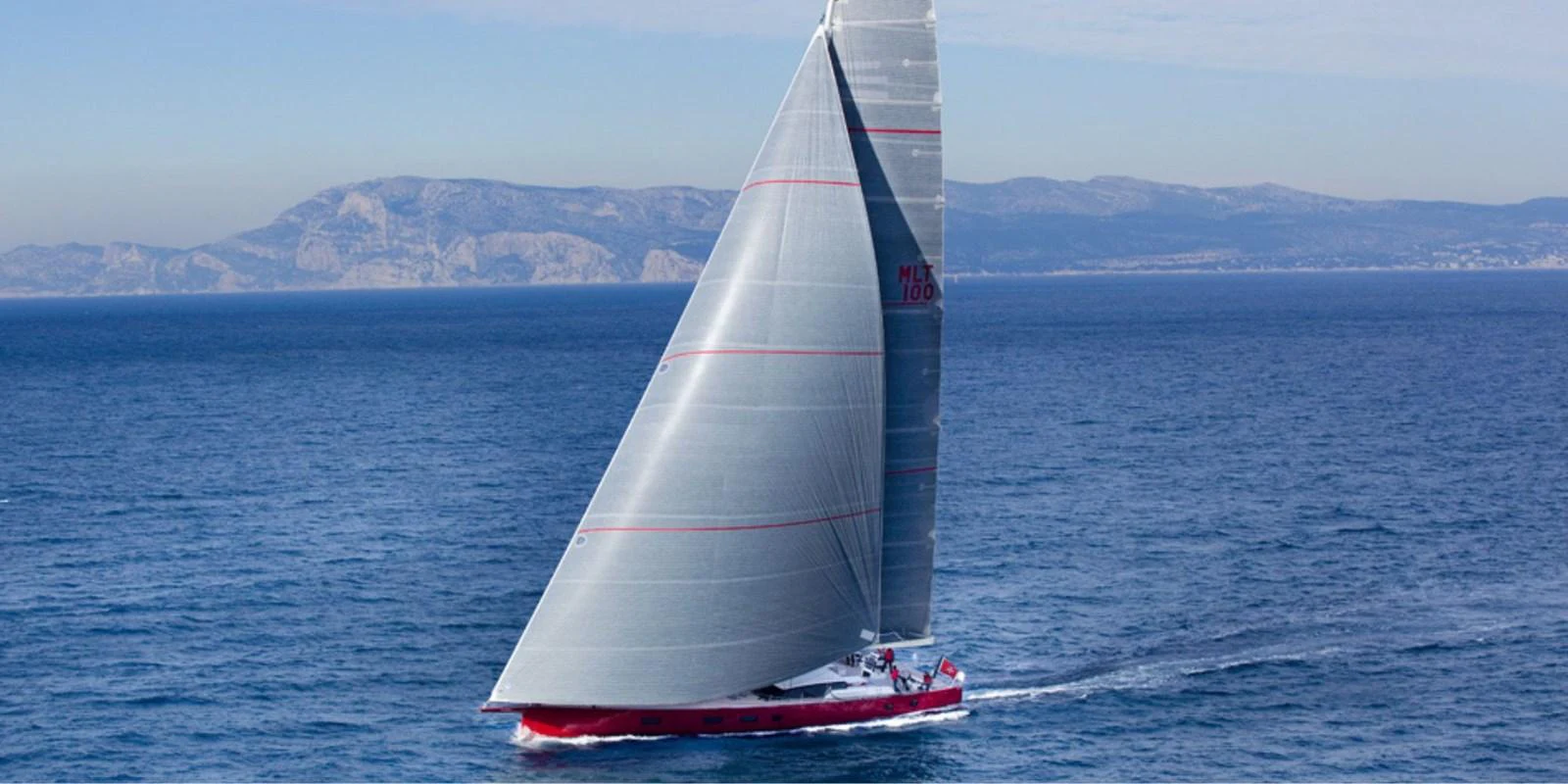 A sleek sailing yacht glides through the open sea with its sails fully extended. aboard NOMAD IV Yacht for Sale