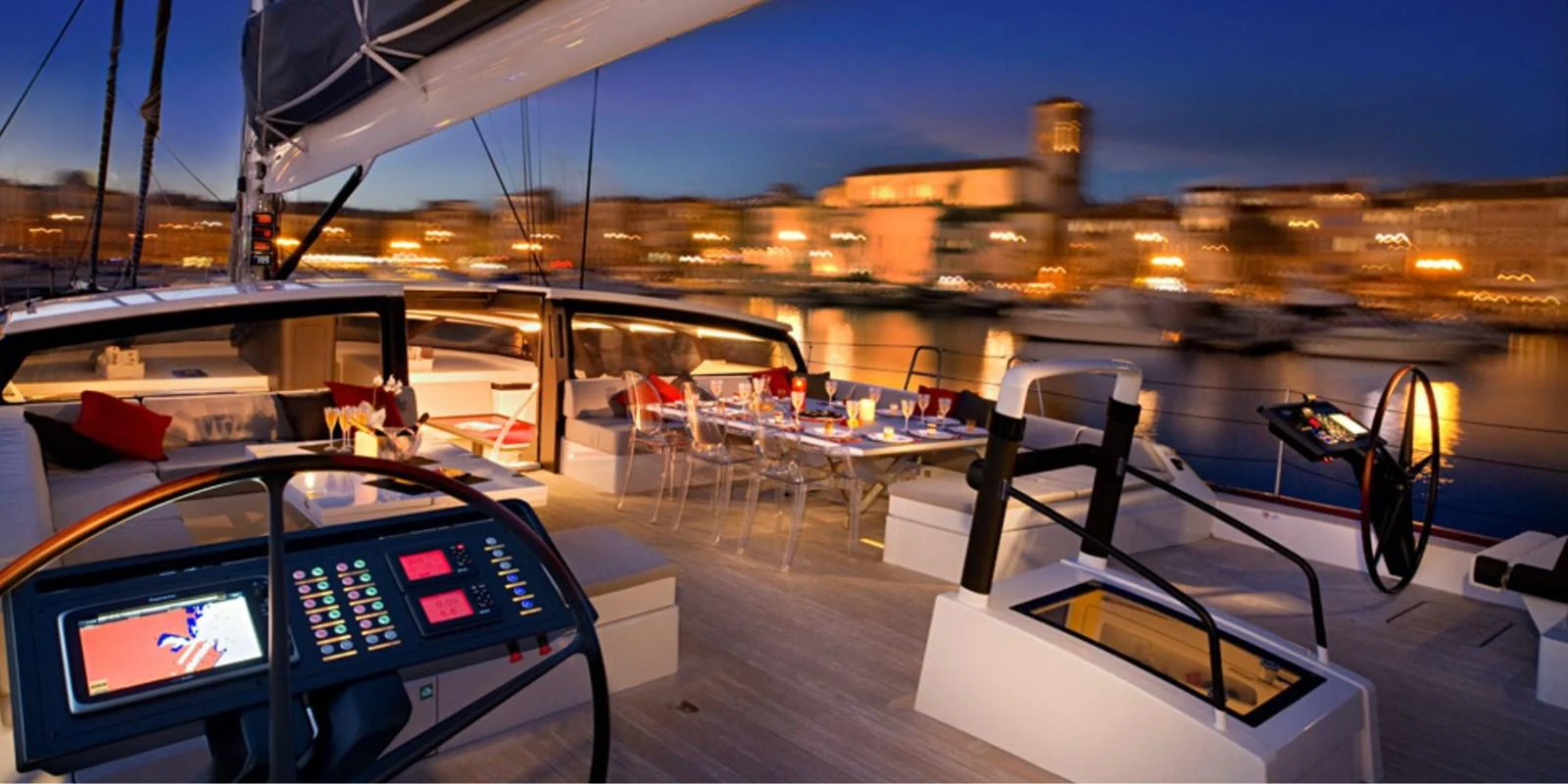 The aft deck of this yacht offers a luxurious dining and lounging area with a stunning evening harbor view. aboard NOMAD IV Yacht for Sale