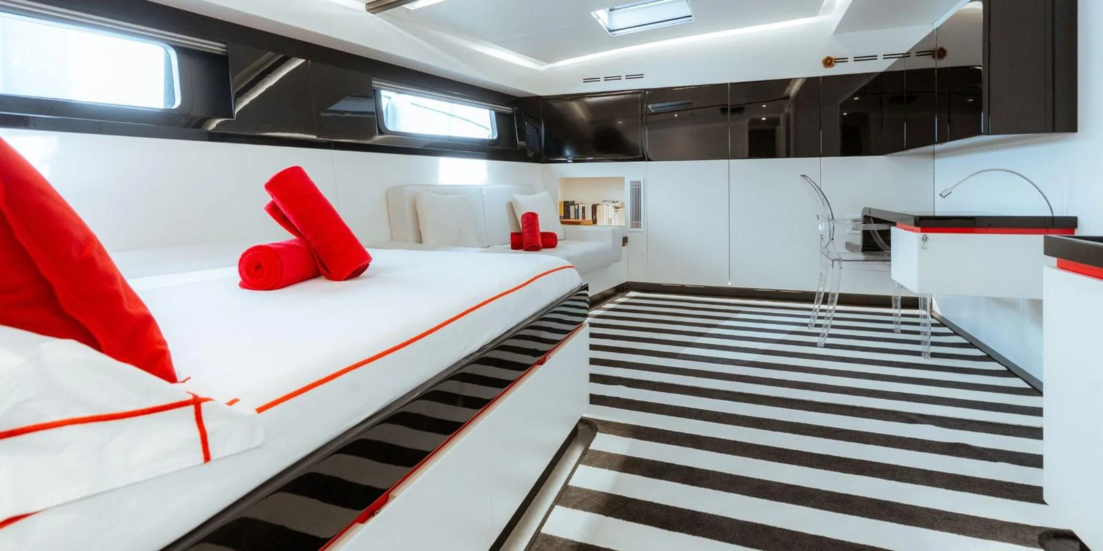The stateroom features a modern design with sleek black and white decor accented by vibrant red details. aboard NOMAD IV Yacht for Sale