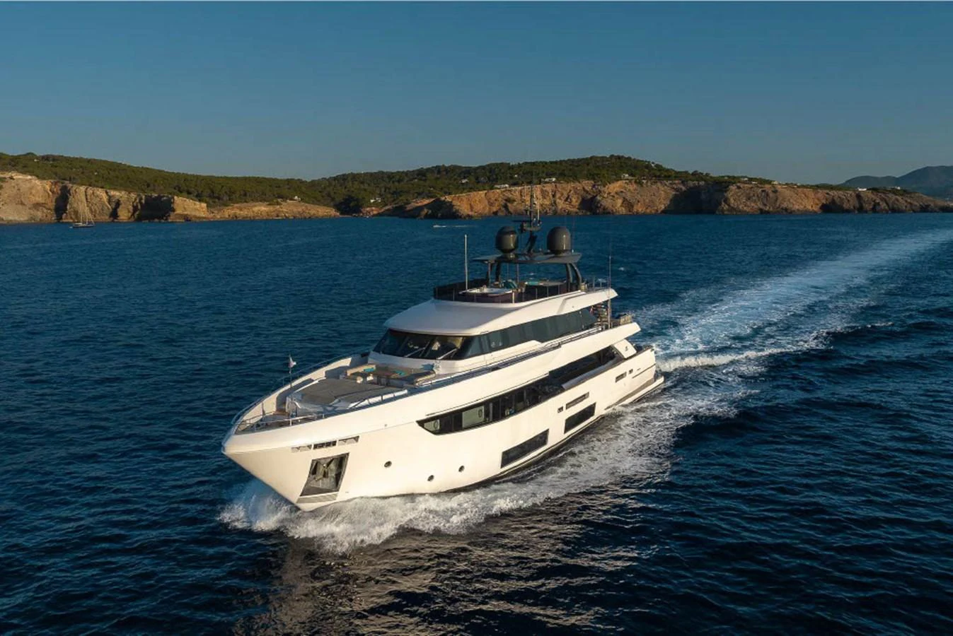 A sleek and modern yacht cruises through calm waters with a scenic coastline in the background. aboard ON Yacht for Sale
