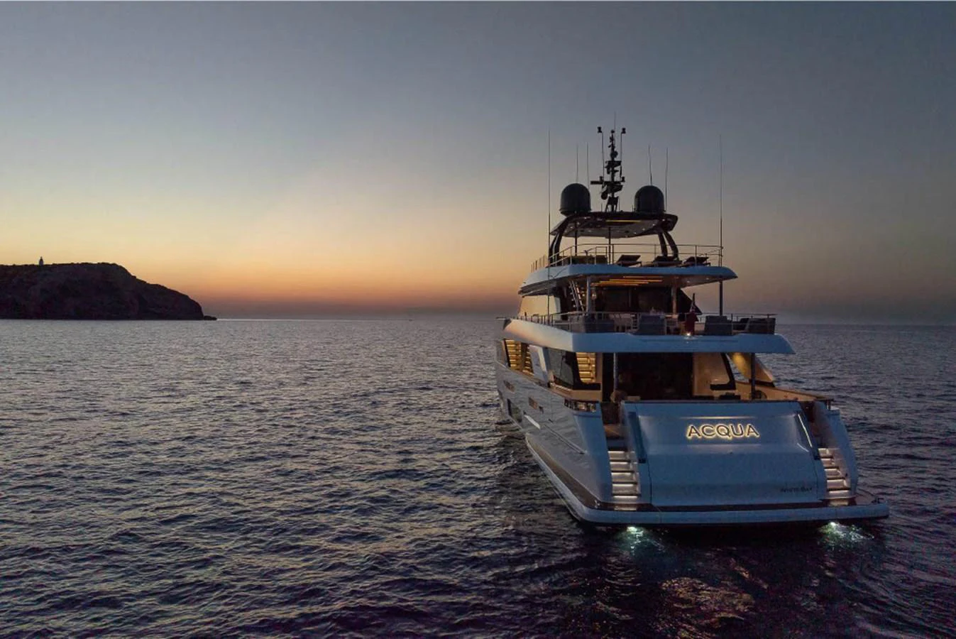 A luxurious yacht is anchored at dusk, with its lights reflecting on the calm sea. aboard ON Yacht for Sale