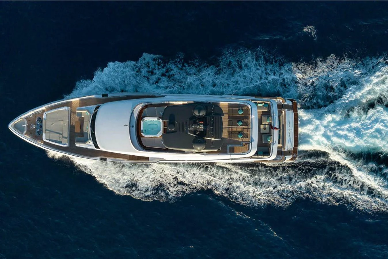 Aerial view of a luxurious yacht cruising through deep blue waters, showcasing its sleek design and spacious deck areas. aboard ON Yacht for Sale