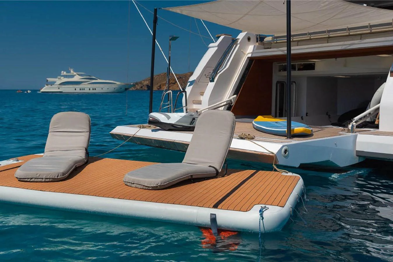 A luxurious floating deck with sun loungers is set up beside a yacht, perfect for relaxation on the water. aboard ON Yacht for Sale