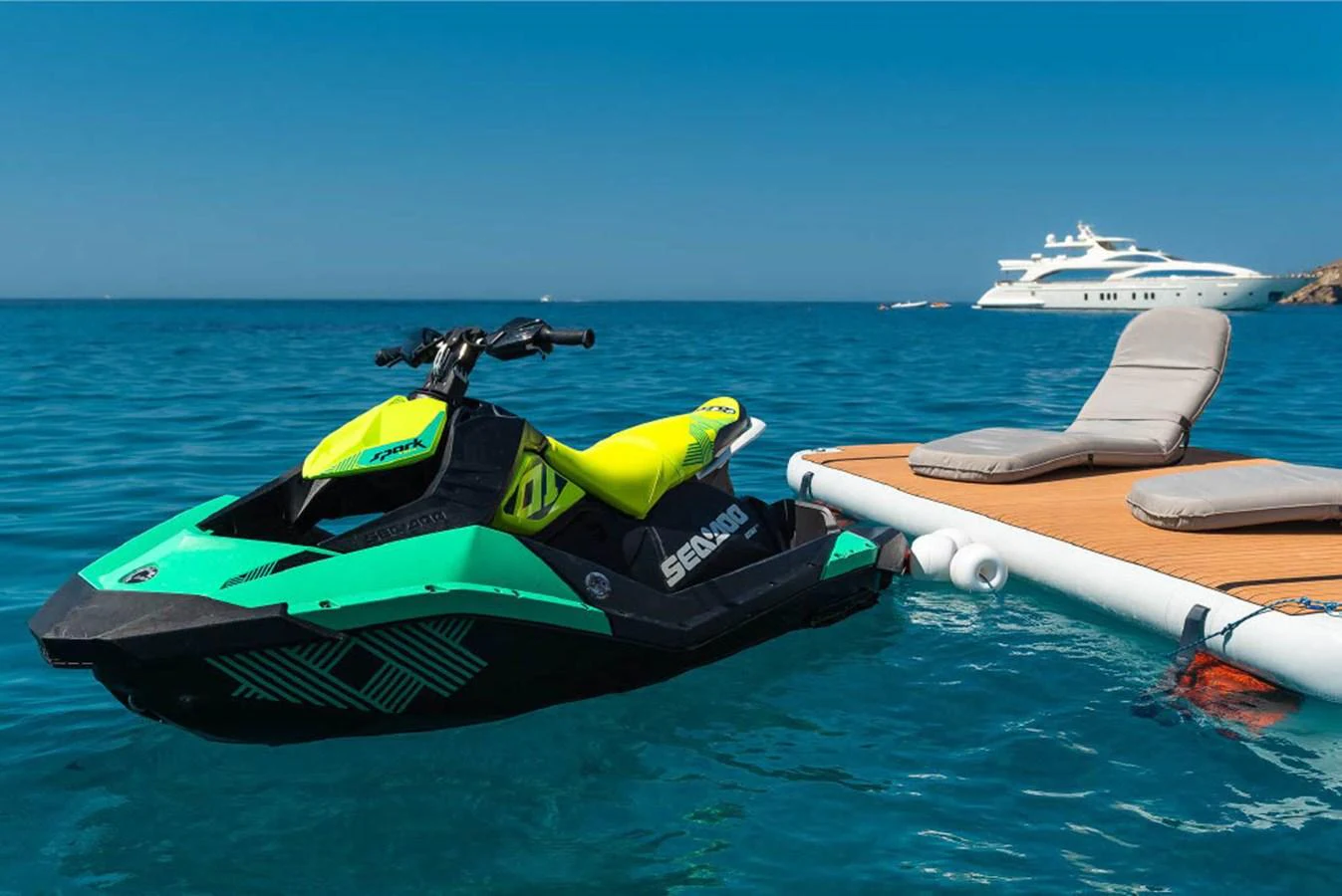 A vibrant jet ski is docked next to a floating platform with a luxurious yacht in the background. aboard ON Yacht for Sale