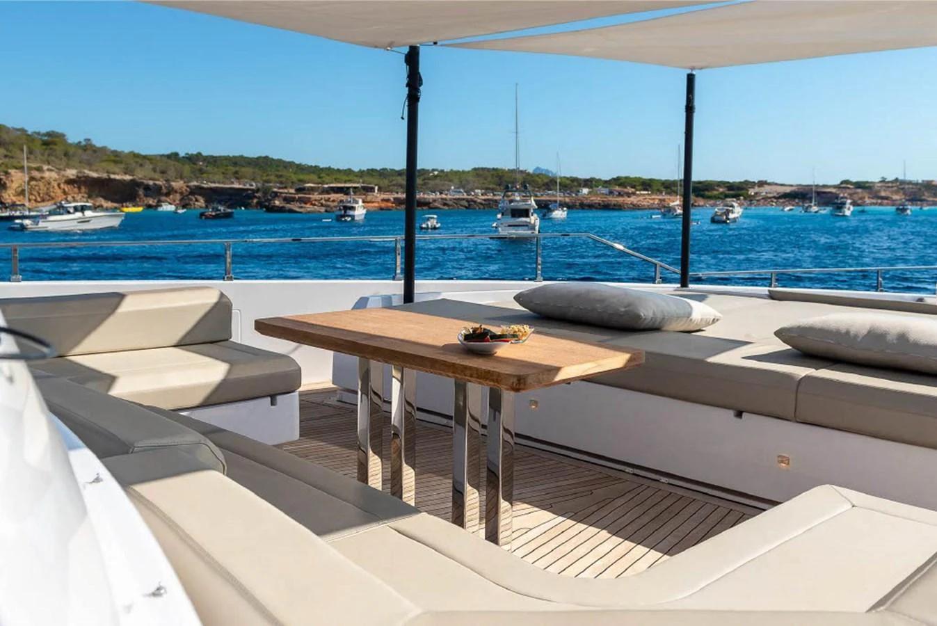 The aft deck features a spacious seating area with a wooden table, perfect for enjoying the scenic views. aboard ON Yacht for Sale