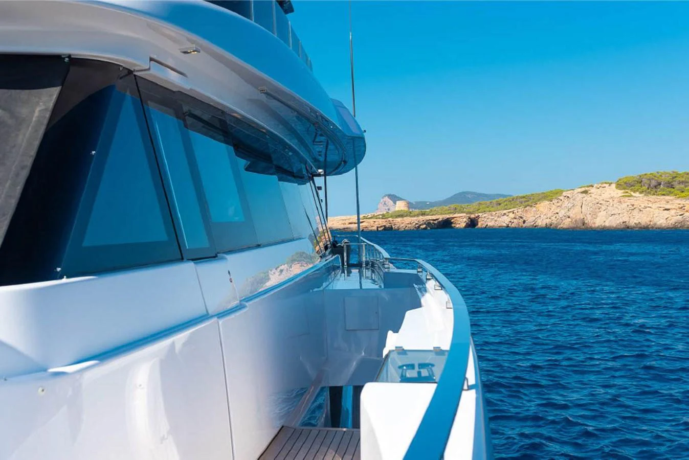 The yacht cruises along a stunning coastline with clear blue waters and a bright sky. aboard ON Yacht for Sale