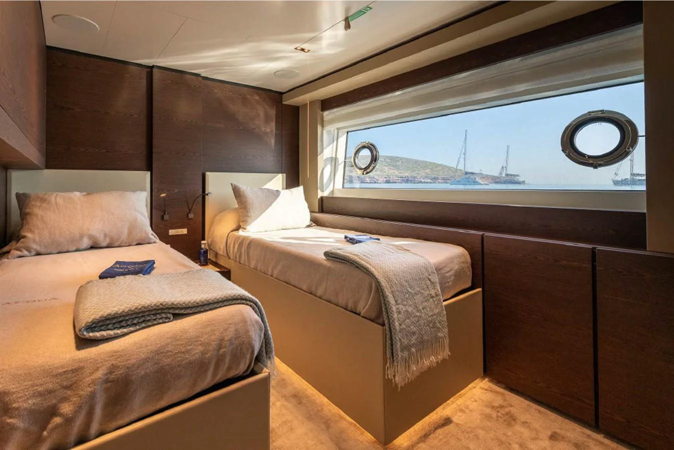 A cozy twin stateroom with large windows offering a scenic view of the sea. aboard ON Yacht for Sale