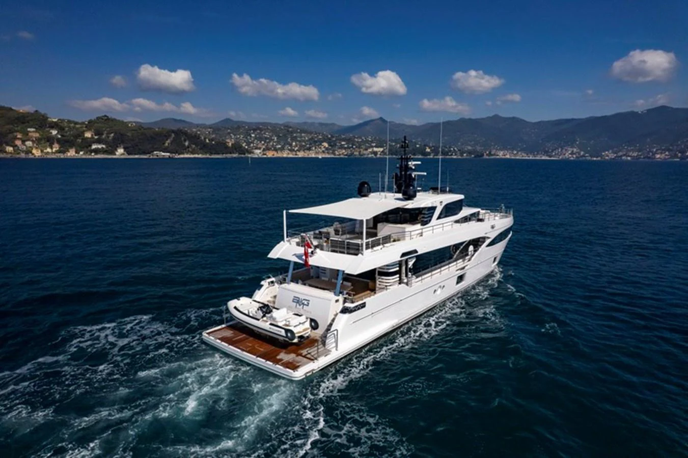 A sleek yacht cruises gracefully on the open water under a clear blue sky. aboard BIG M Yacht for Sale