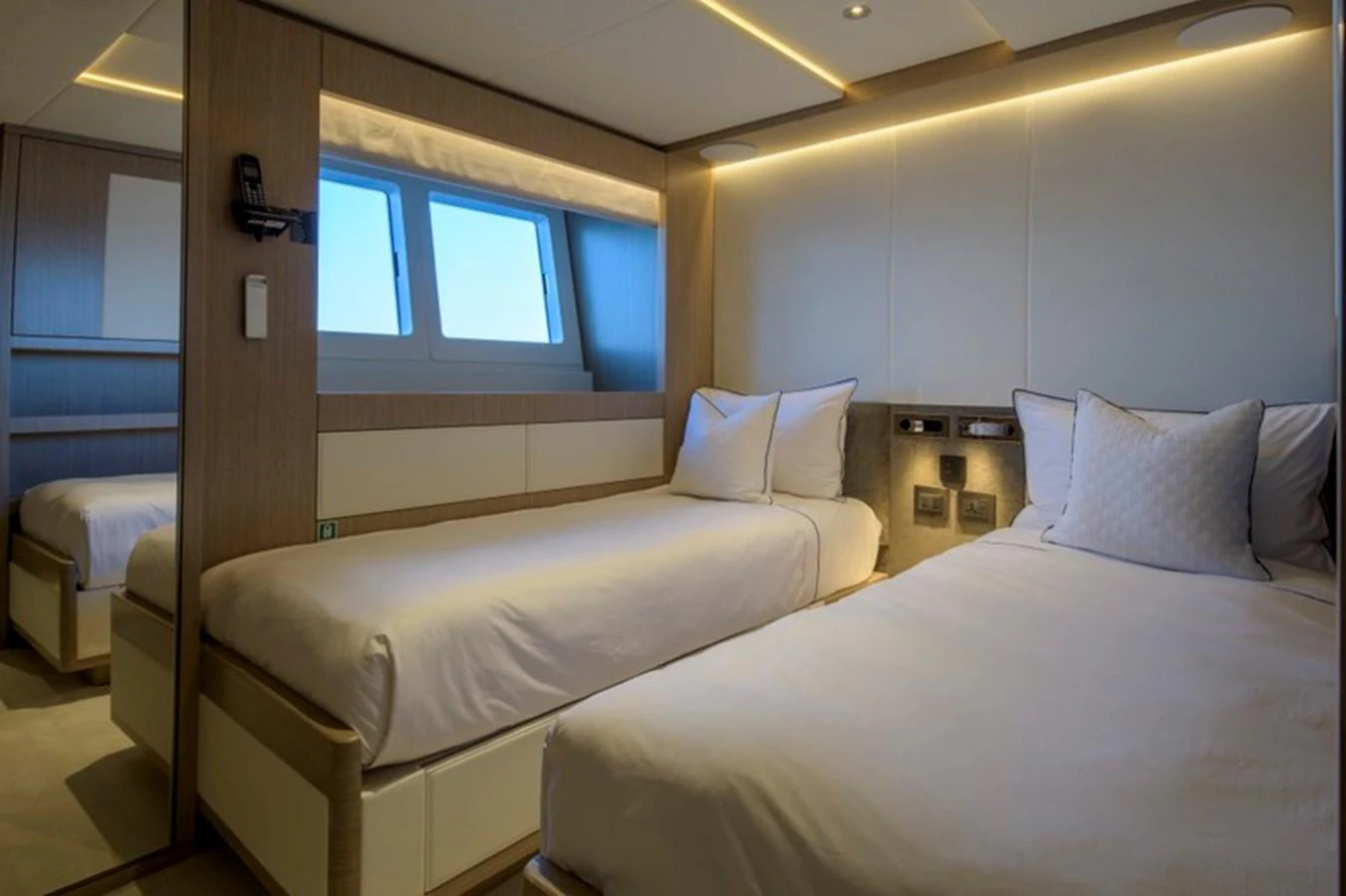 The guest stateroom features twin beds with modern lighting and a serene atmosphere. aboard BIG M Yacht for Sale