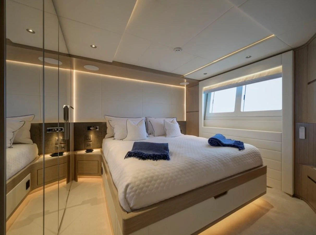 The stateroom features a luxurious bed with elegant lighting and ample natural light from the windows. aboard BIG M Yacht for Sale