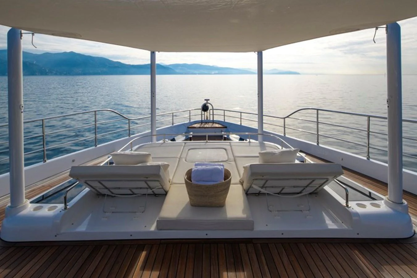 The aft deck offers a serene lounging area with a stunning view of the sea and distant mountains. aboard BIG M Yacht for Sale