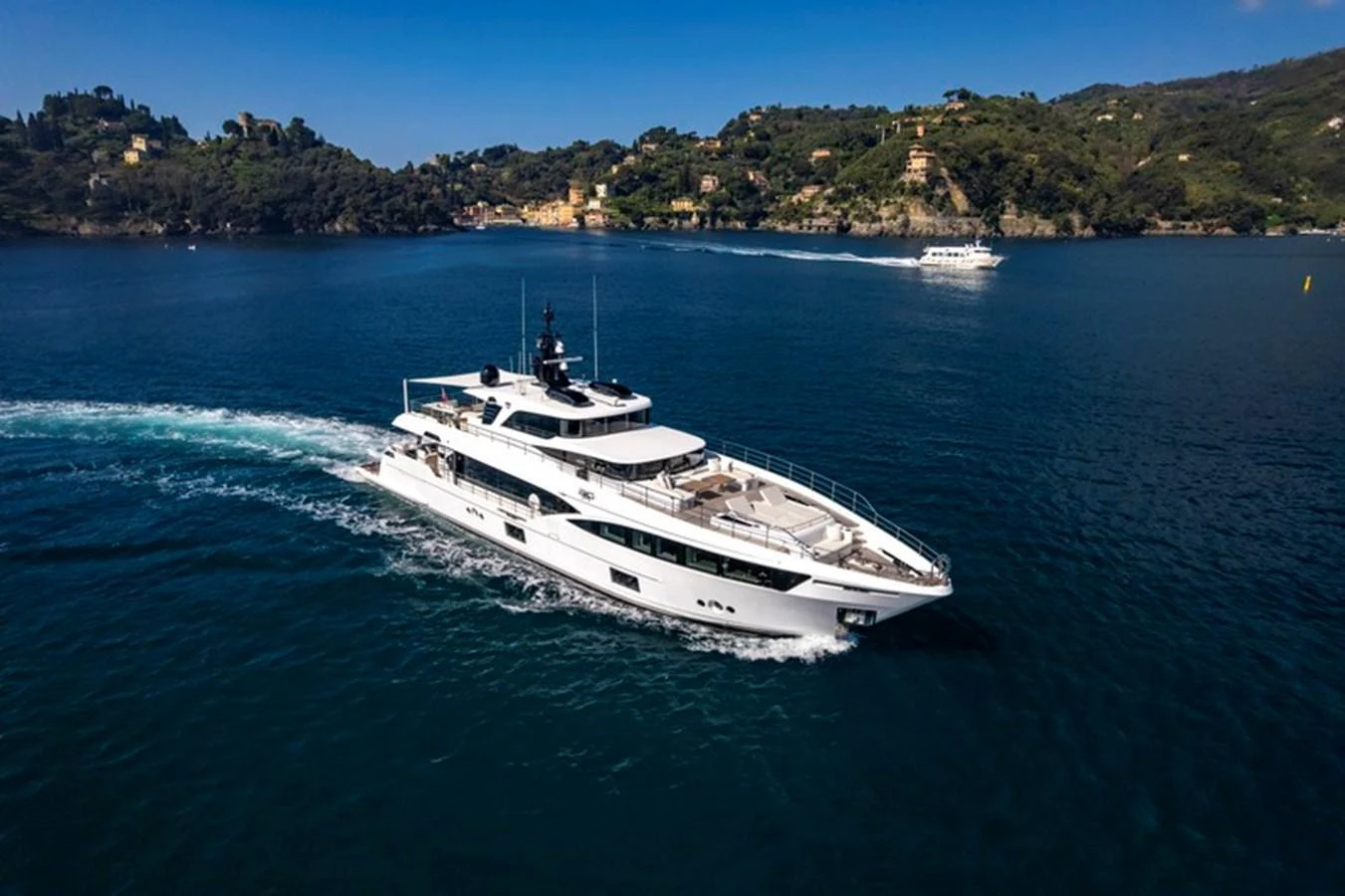 A sleek and modern yacht cruises through calm waters with a scenic coastal backdrop. aboard BIG M Yacht for Sale