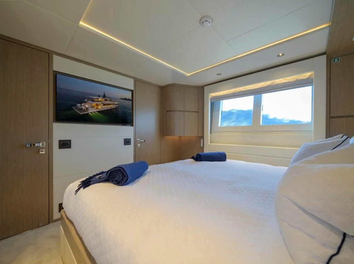 A cozy guest stateroom with a large bed, modern decor, and a window offering a scenic view. aboard BIG M Yacht for Sale