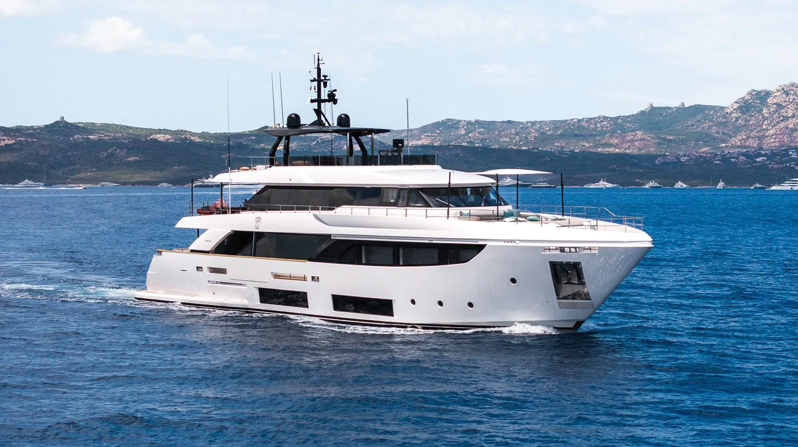 A sleek and modern yacht cruises through calm blue waters with a scenic coastline in the background. aboard QUEEN J III Yacht for Sale