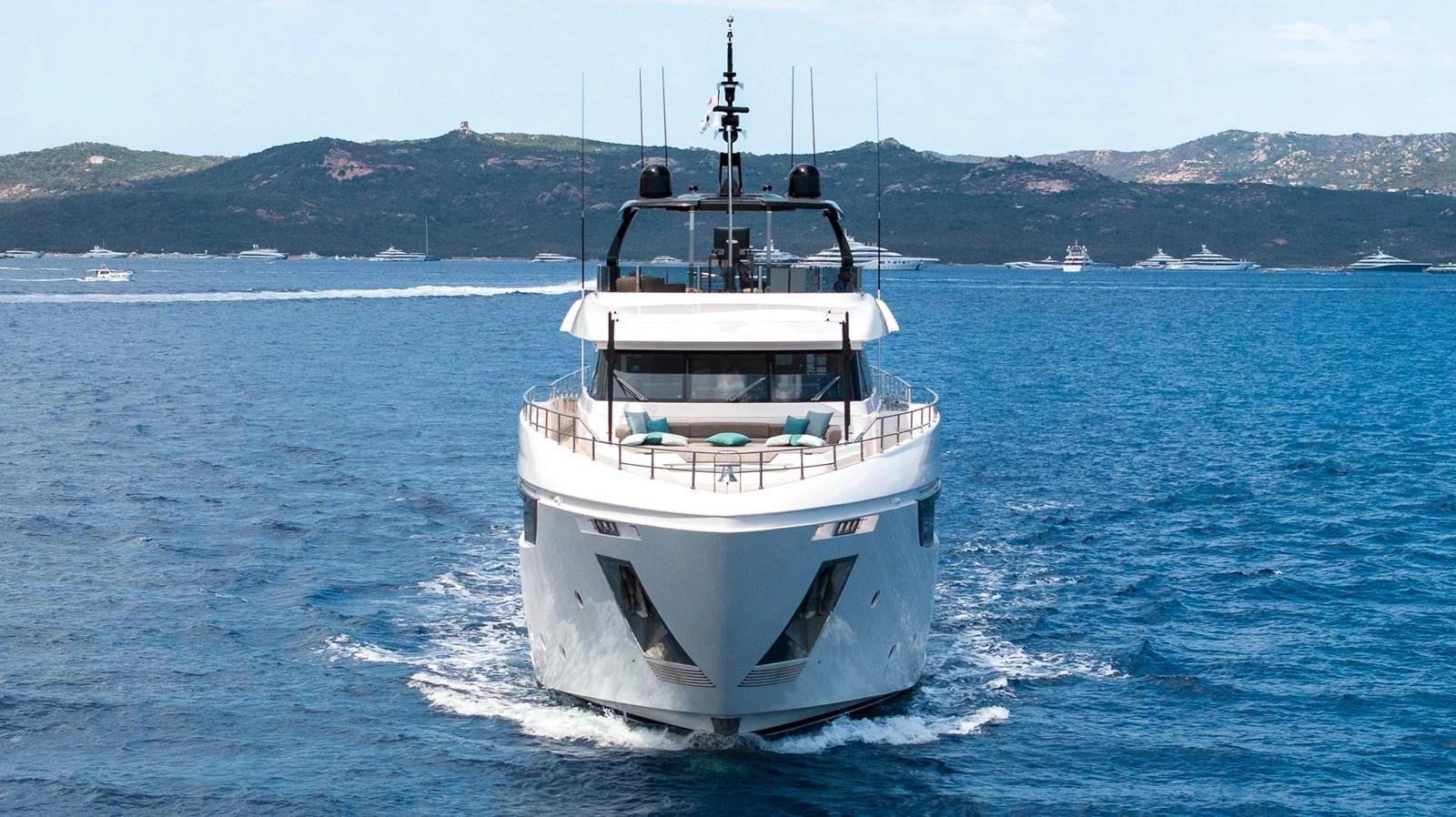 A sleek yacht cruises forward on a calm sea with a scenic coastline in the background. aboard QUEEN J III Yacht for Sale