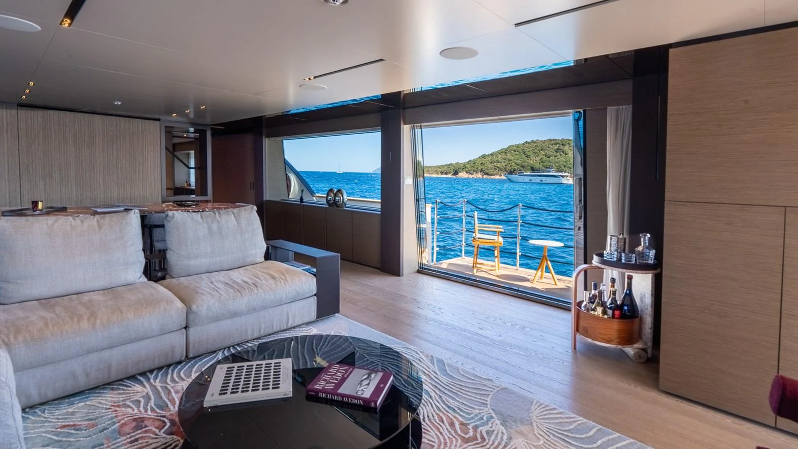 The salon offers a spacious and elegant area with a stunning view of the sea through large windows and an open door leading to the deck. aboard QUEEN J III Yacht for Sale