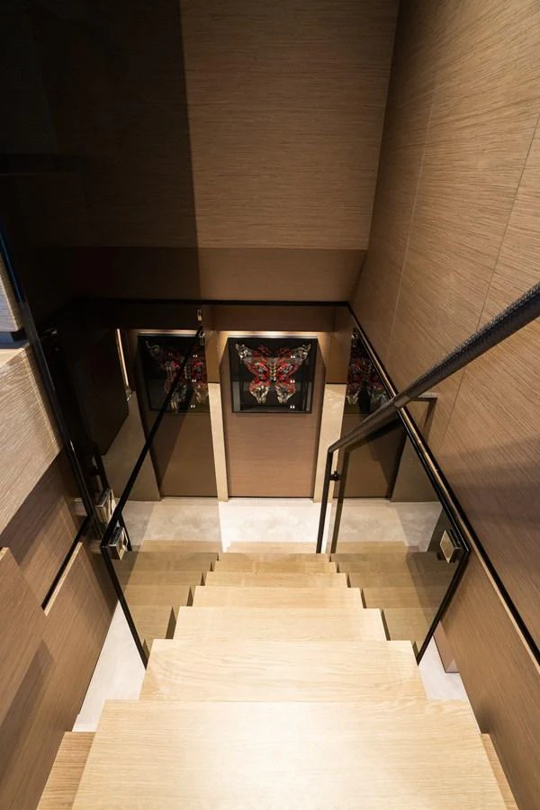 A stylish staircase with wooden steps and modern decor leads to the lower deck. aboard QUEEN J III Yacht for Sale
