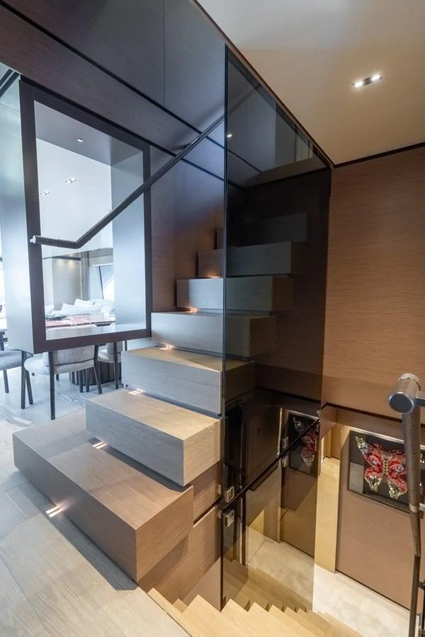 A modern and sleek staircase with glass railings and wooden steps, leading to a luxurious interior space. aboard QUEEN J III Yacht for Sale