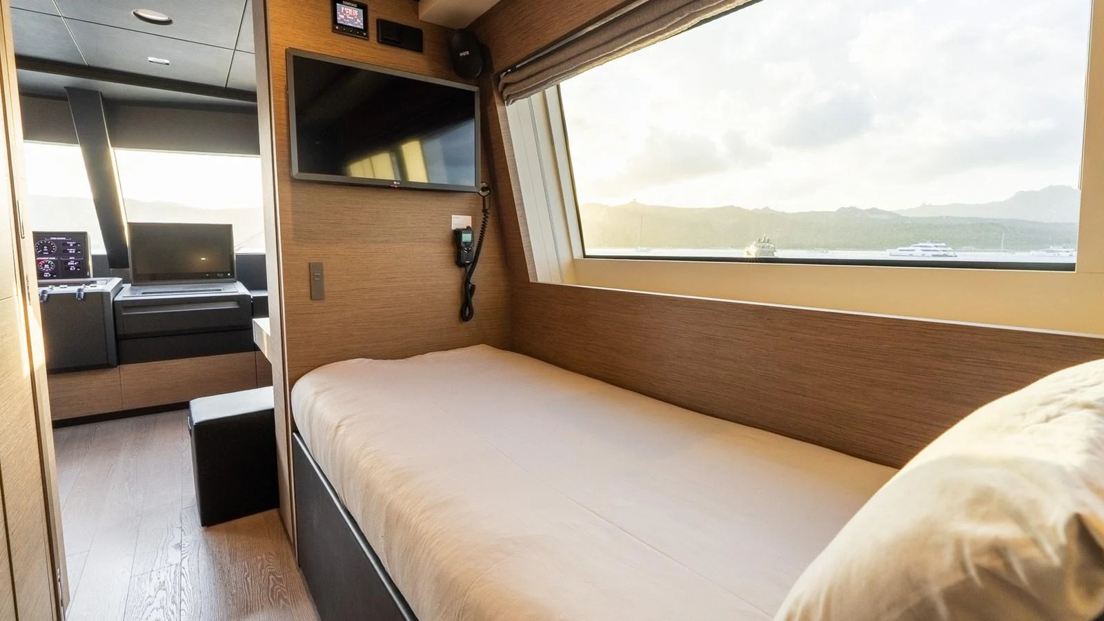 A cozy cabin with a single bed, large window, and modern amenities. aboard QUEEN J III Yacht for Sale