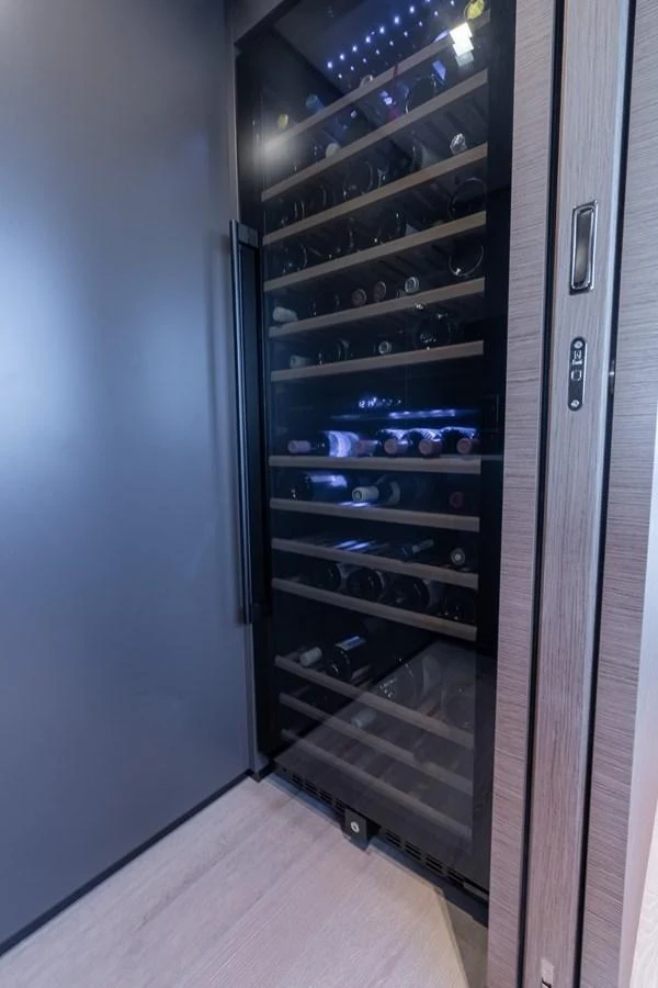 A sleek, modern wine cellar with multiple shelves stocked with wine bottles. aboard QUEEN J III Yacht for Sale
