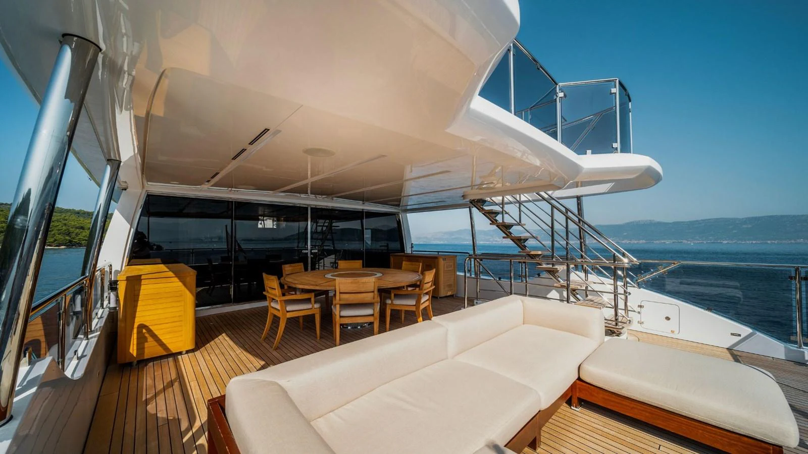 The yacht's aft deck features a spacious seating area with a large sofa and dining table, perfect for outdoor relaxation and dining. aboard AFINA Yacht for Sale