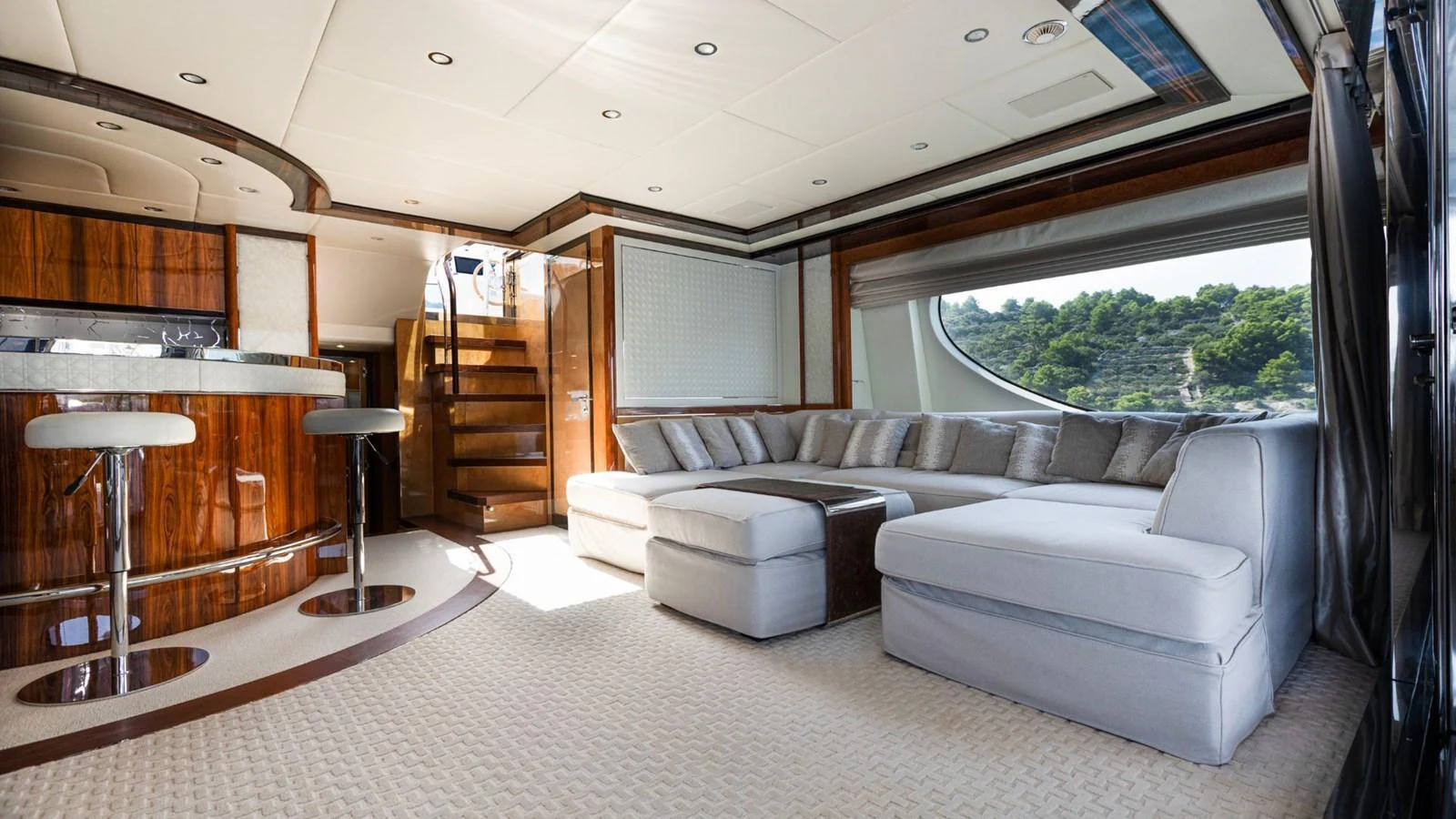 The yacht's salon features a luxurious seating area with a large, comfortable sofa and stylish bar stools. aboard AFINA Yacht for Sale
