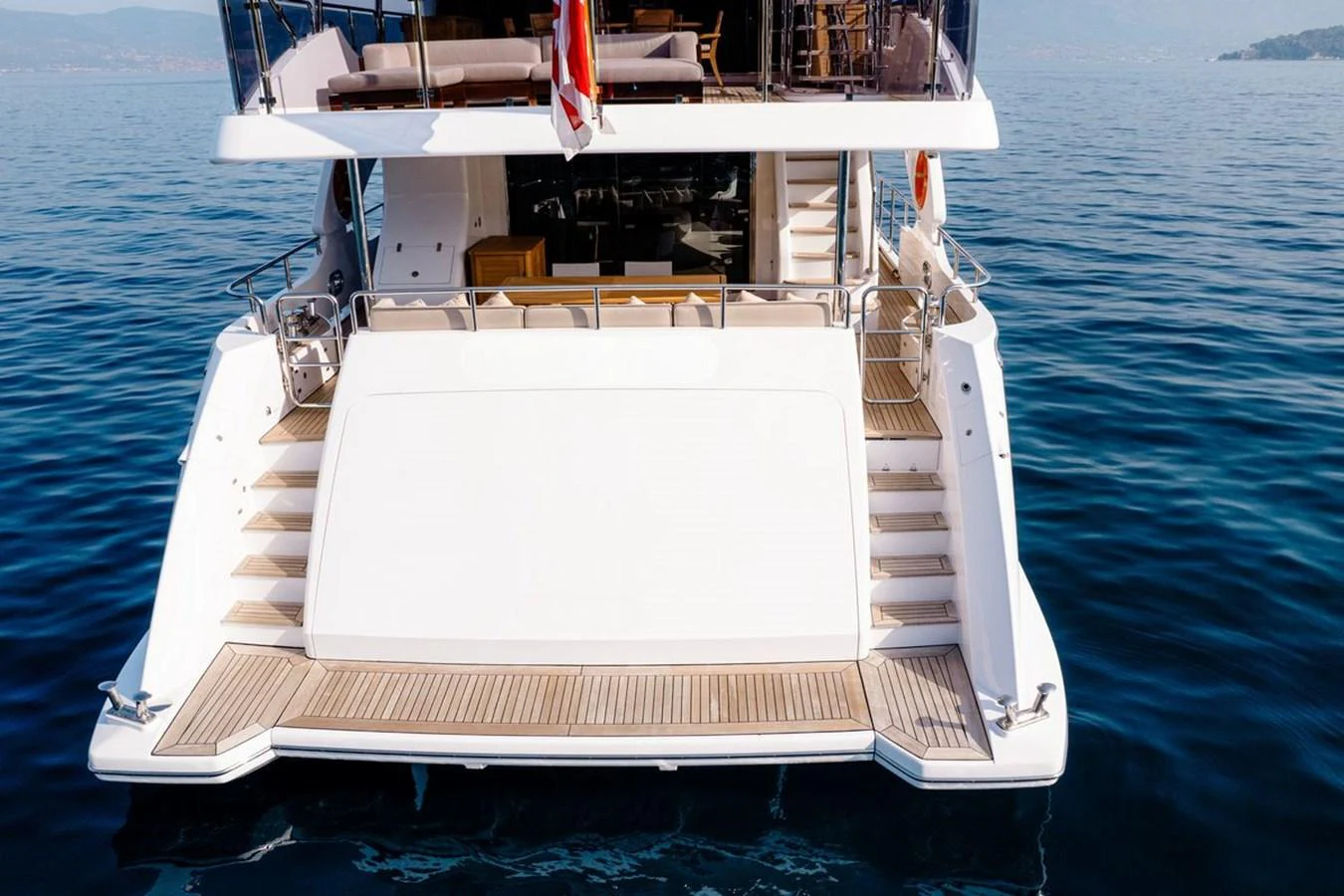 The yacht's aft deck features a spacious swim platform and elegant staircases leading to the upper deck. aboard AFINA Yacht for Sale