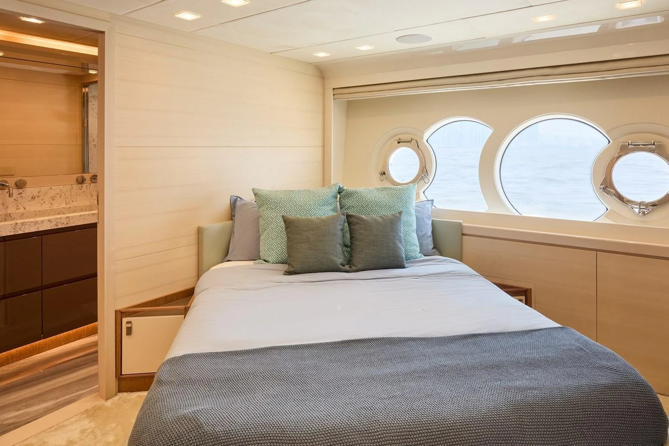 A cozy stateroom with a comfortable bed and large circular windows offering a serene view of the sea. aboard MIRAE Yacht for Sale