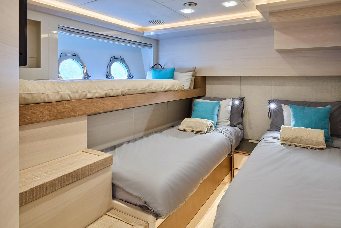 The guest stateroom features twin beds and a cozy, modern design with soft lighting and porthole windows. aboard MIRAE Yacht for Sale