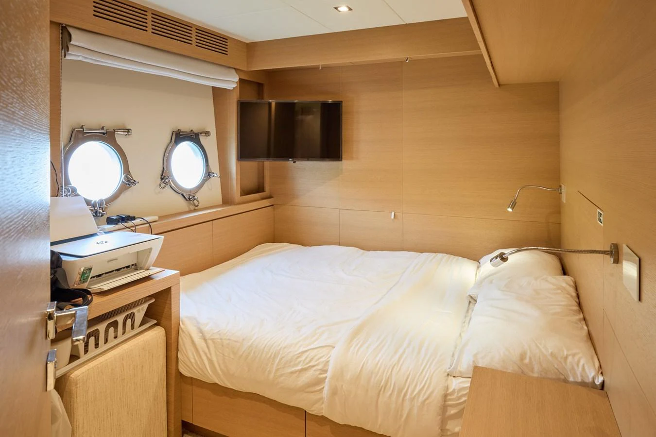 A cozy stateroom featuring a comfortable bed, porthole windows, and a wall-mounted TV. aboard MIRAE Yacht for Sale