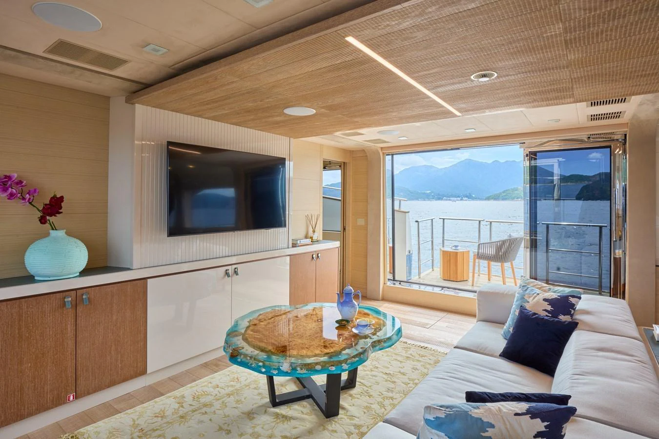 The salon offers a cozy and elegant space with a large window providing stunning views of the water and mountains. aboard MIRAE Yacht for Sale