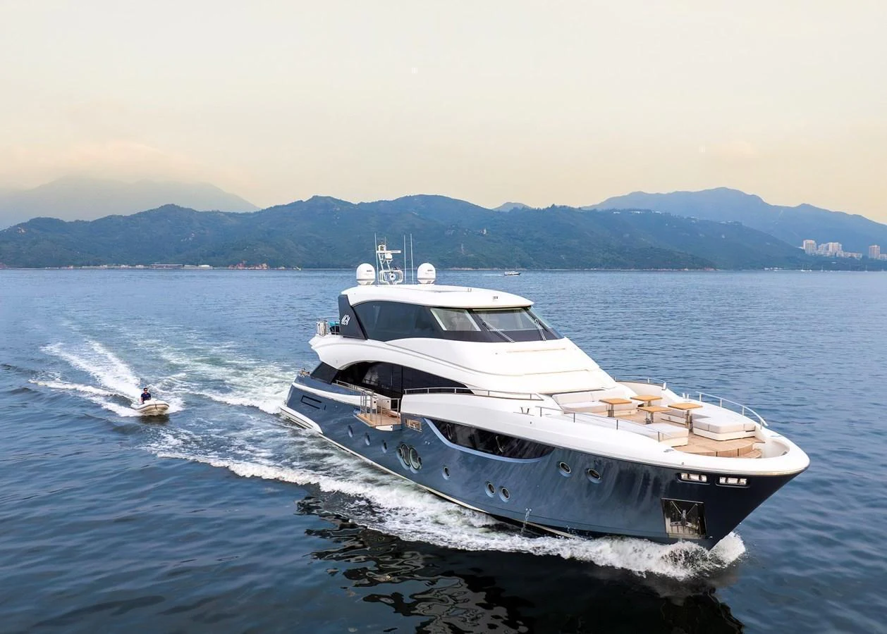 A luxurious yacht cruises on calm waters with scenic mountains in the background. aboard MIRAE Yacht for Sale
