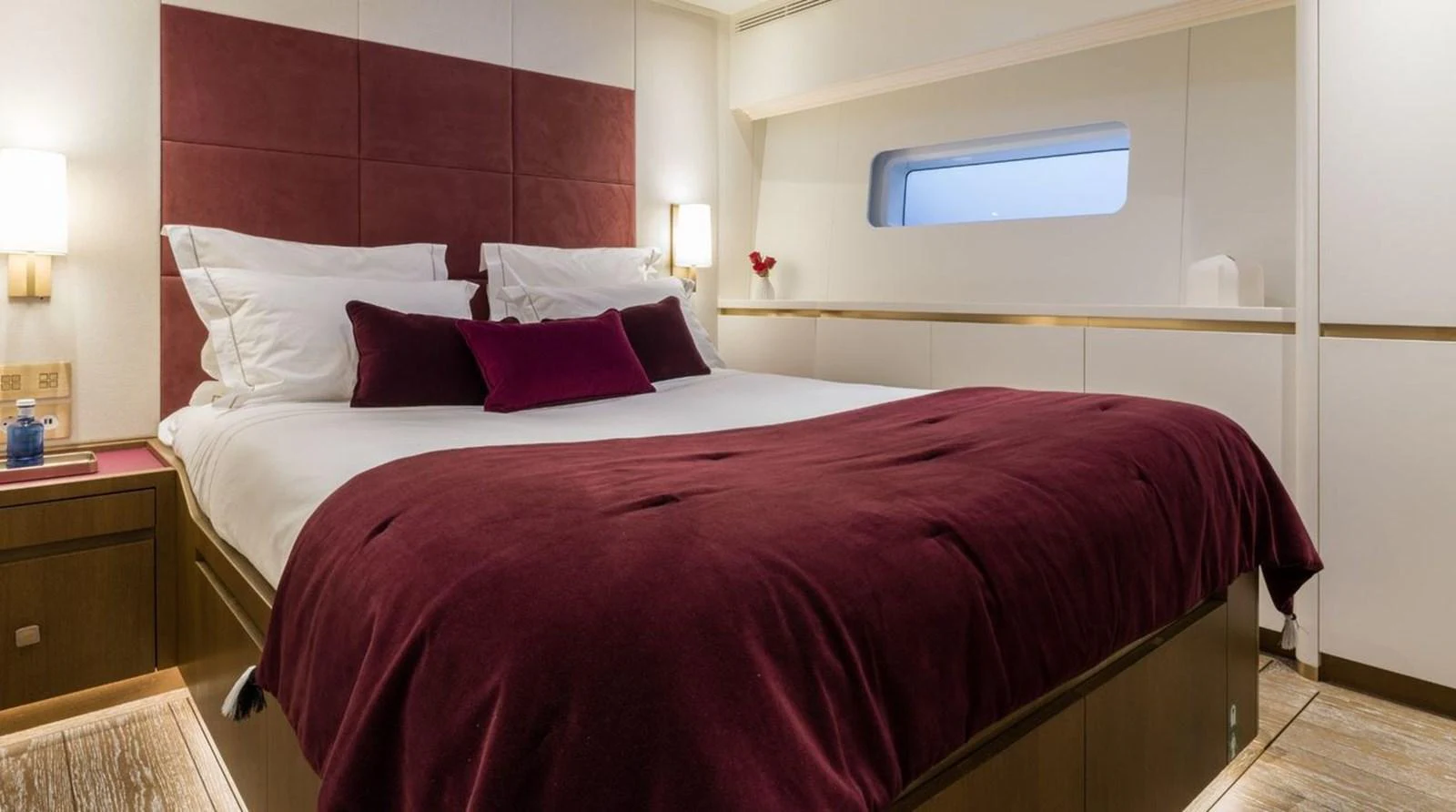 The stateroom features a plush bed with rich burgundy accents and modern lighting. aboard FANCY Yacht for Sale