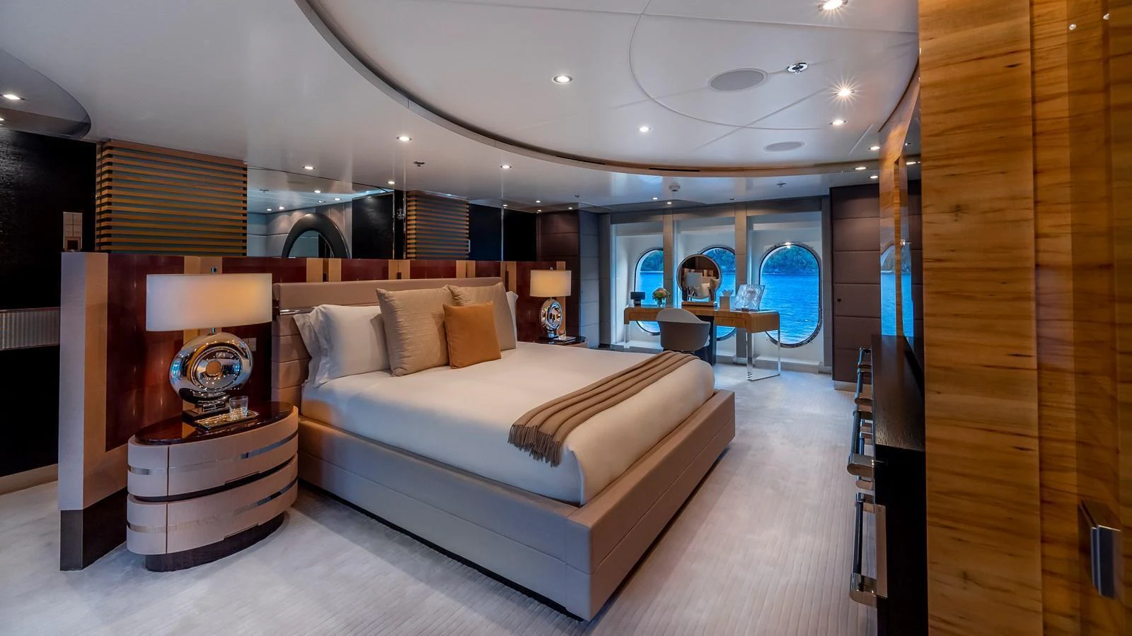 The master stateroom features a luxurious bed, elegant wood finishes, and large windows with ocean views. aboard SCOTT FREE Yacht for Sale