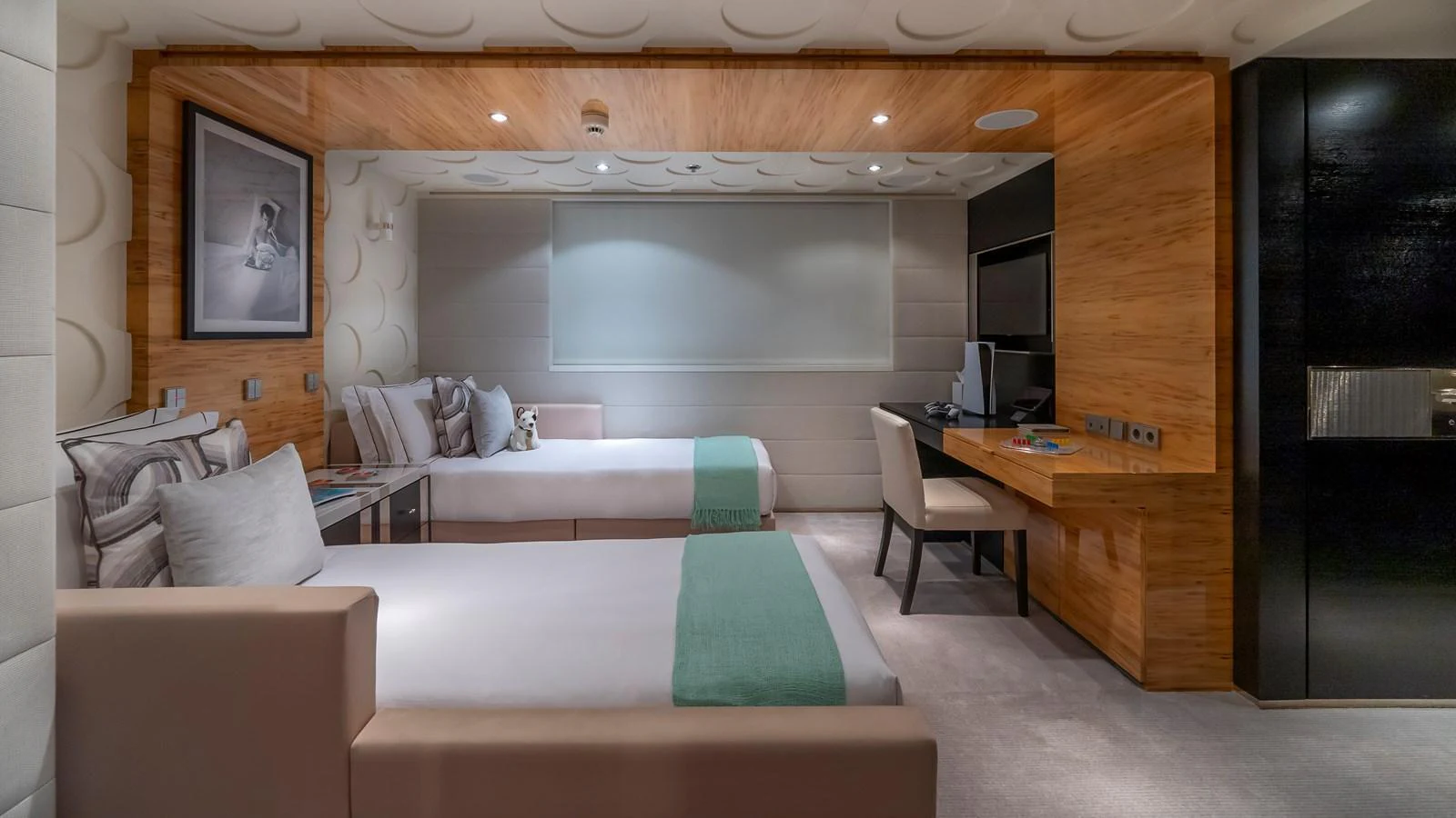 The guest stateroom features twin beds, a cozy seating area, and a modern workspace, all in a warm, inviting ambiance. aboard SCOTT FREE Yacht for Sale