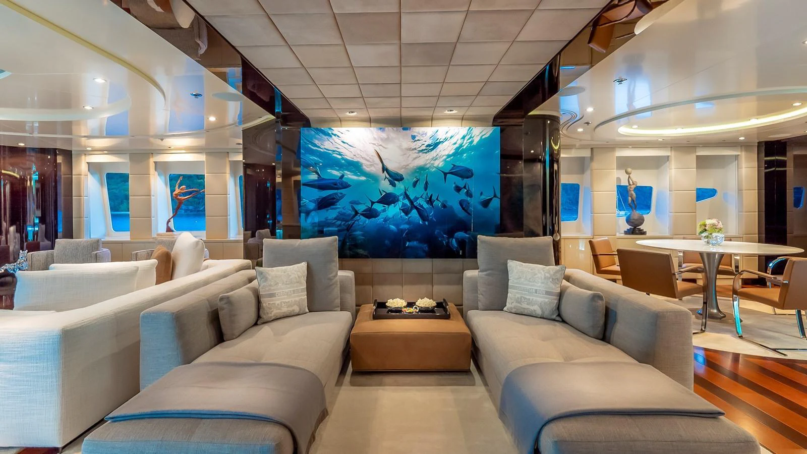 The salon features luxurious seating and a stunning underwater-themed wall art, creating a serene and elegant atmosphere. aboard SCOTT FREE Yacht for Sale