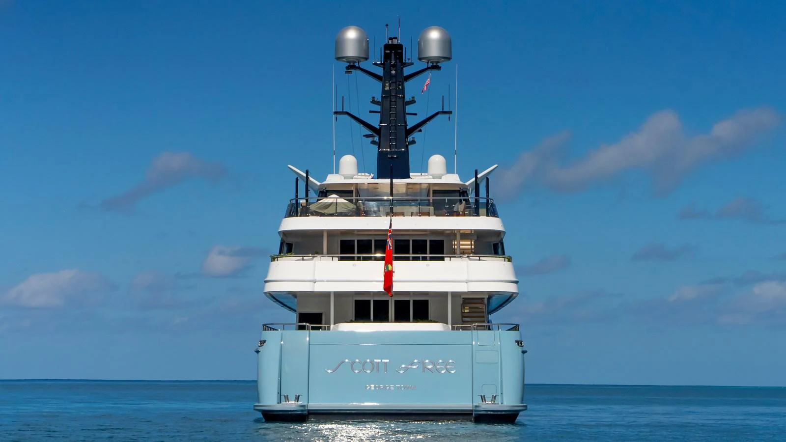 The yacht is seen from the rear, showcasing its sleek design and modern features against a serene ocean backdrop. aboard SCOTT FREE Yacht for Sale