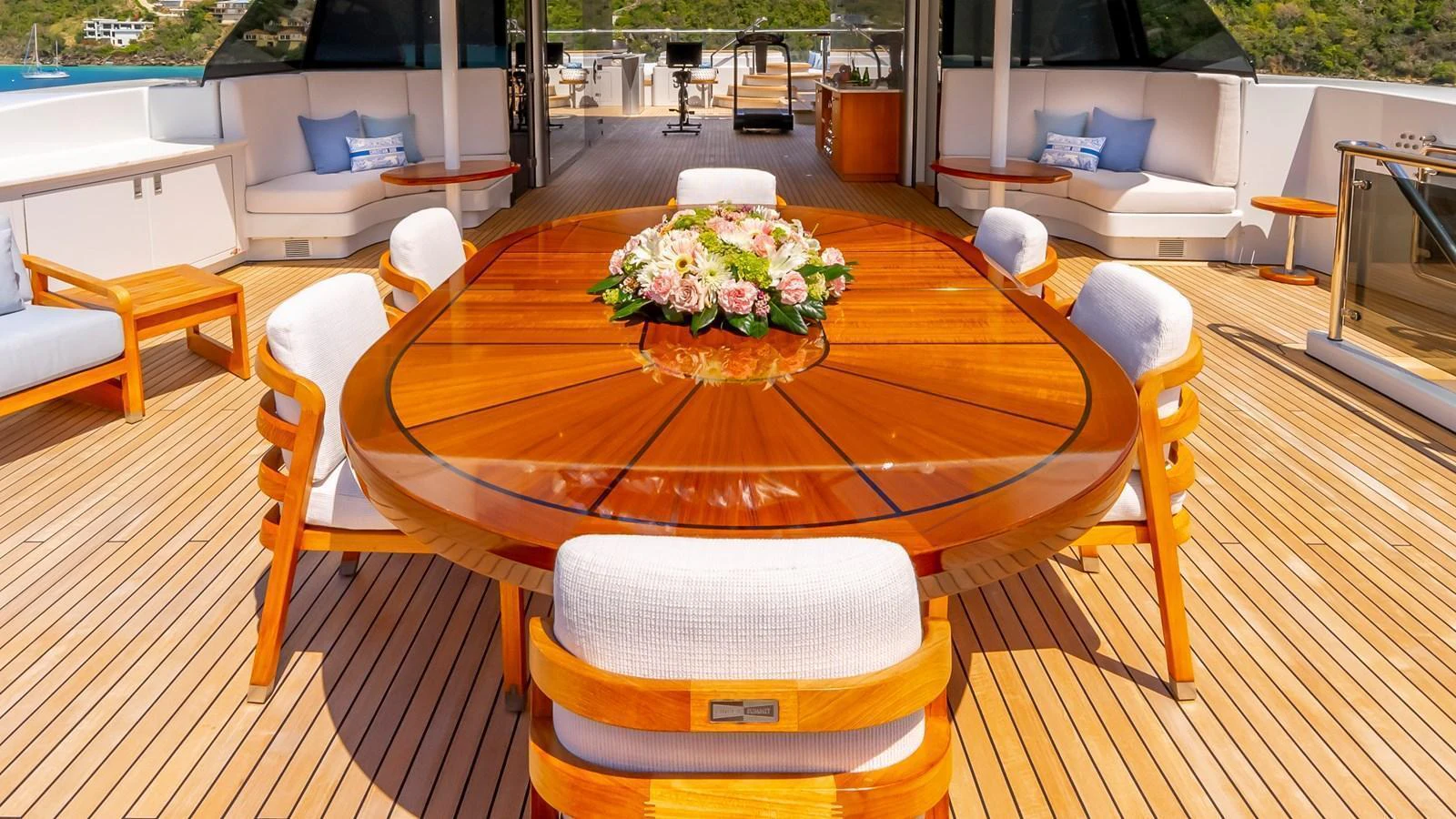The aft deck features a beautifully crafted wooden dining table with plush seating, perfect for alfresco dining. aboard SCOTT FREE Yacht for Sale