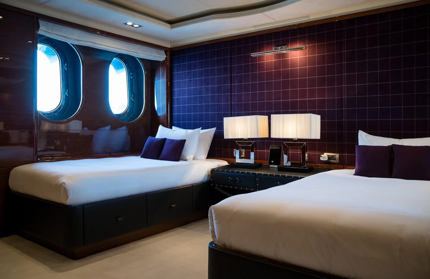 The guest stateroom features two comfortable beds with elegant decor and ample natural light from the portholes. aboard VISION Yacht for Sale