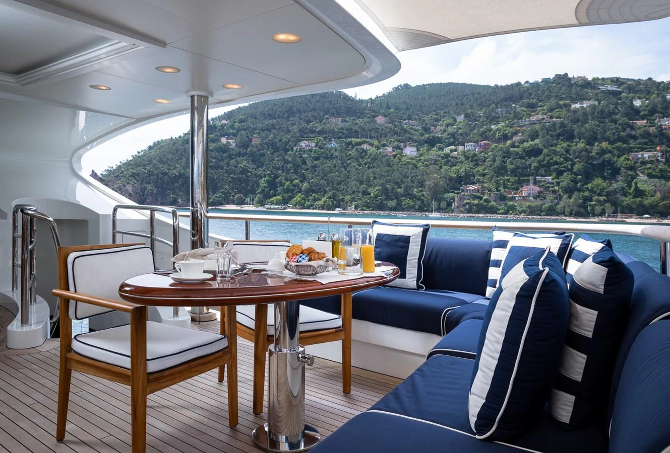 The aft deck features a cozy dining area with a stunning view of the surrounding landscape. aboard VISION Yacht for Sale
