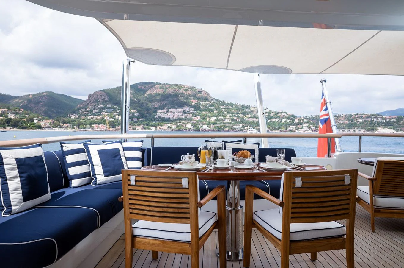 The aft deck features a stylish dining area with a scenic view of the coastline. aboard VISION Yacht for Sale