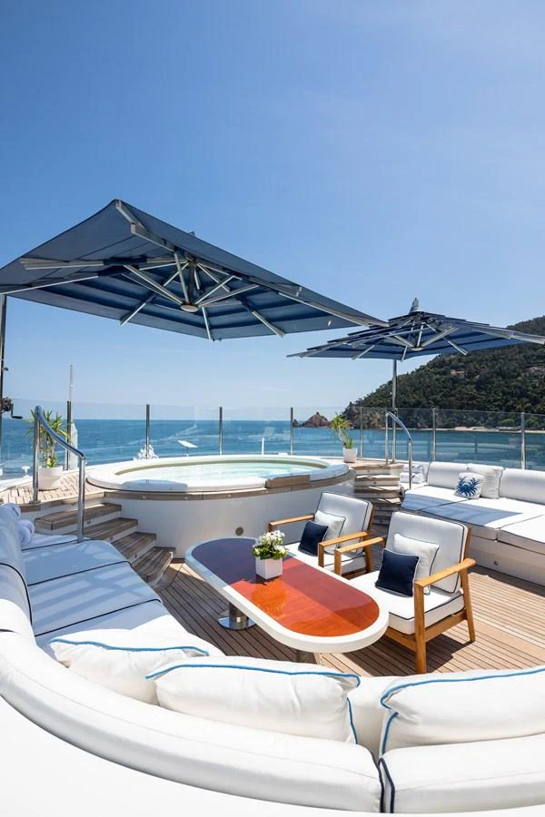 The sundeck features a luxurious jacuzzi surrounded by comfortable seating and shaded by elegant umbrellas. aboard VISION Yacht for Sale