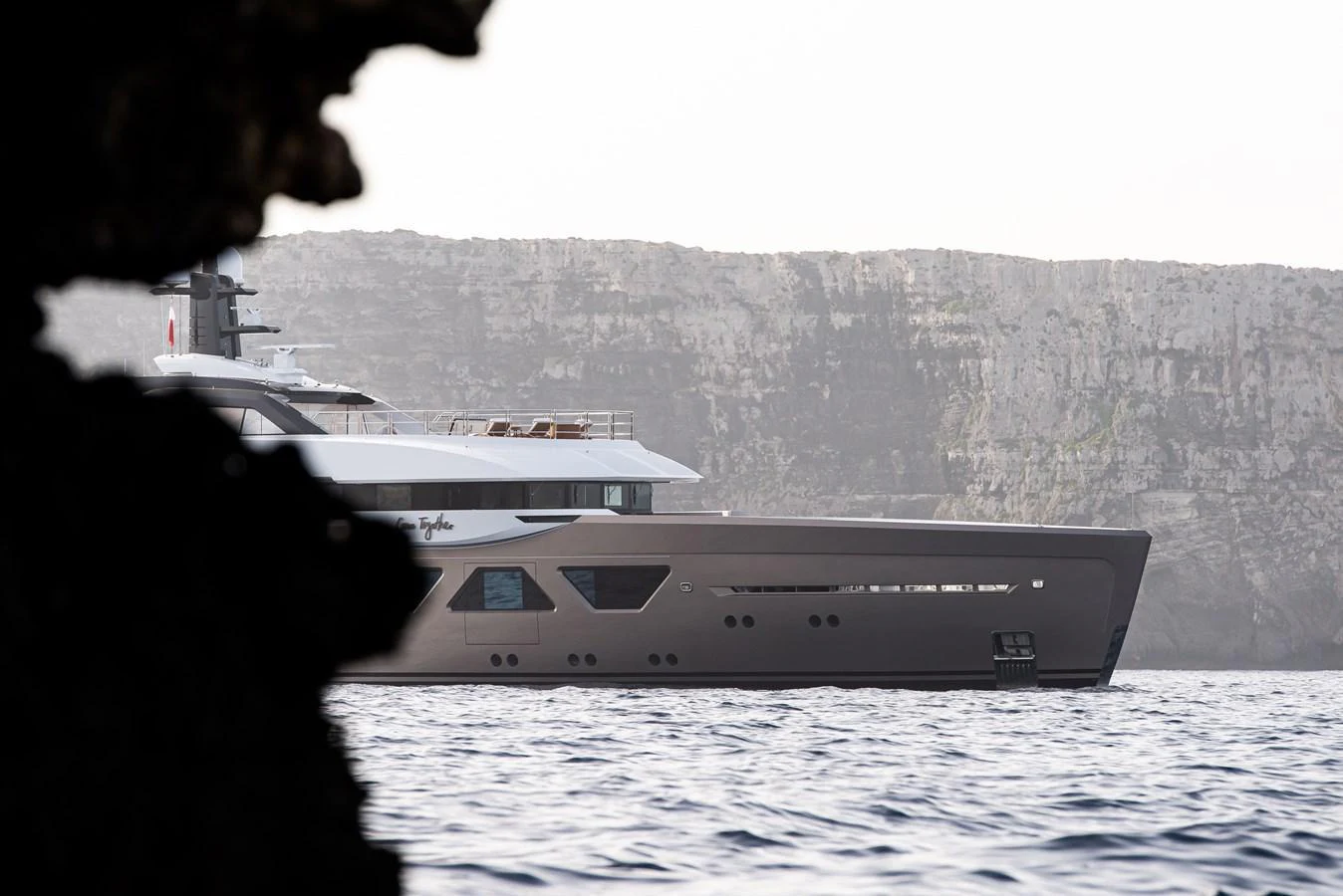 A sleek yacht cruises along a rocky coastline, showcasing its modern design and luxurious features. aboard AMELS 60 Yacht for Sale