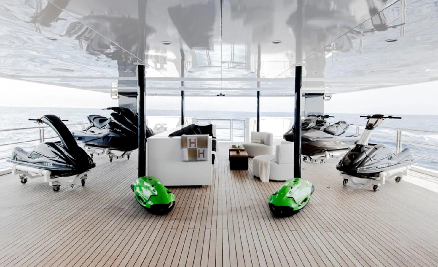 The yacht features a spacious toy storage area with multiple jet skis and comfortable seating. aboard IDOL Yacht for Sale