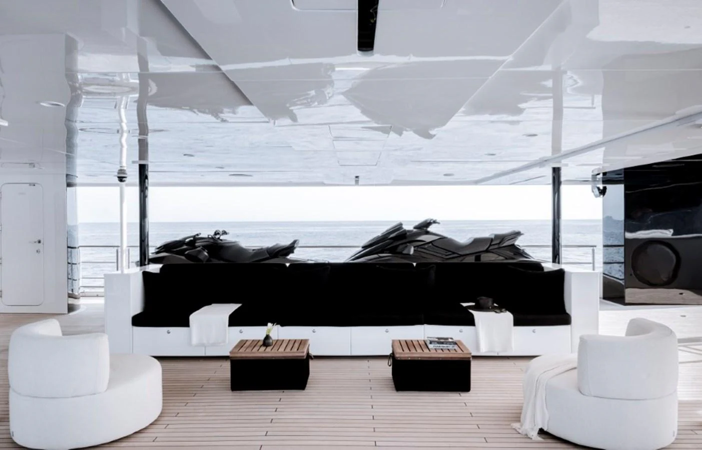 The aft deck features a sleek, modern seating area with a view of the water and jet skis. aboard IDOL Yacht for Sale