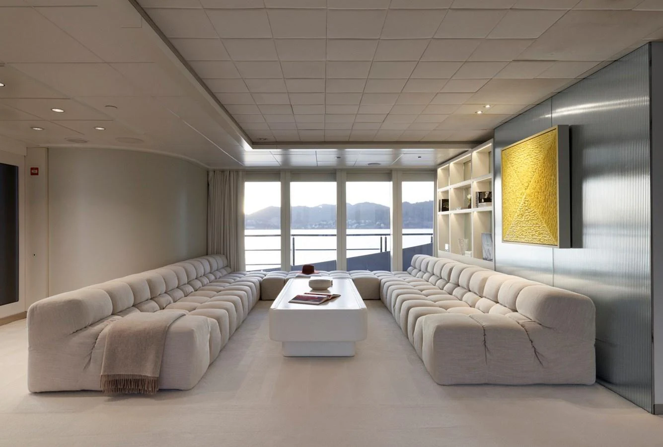 The yacht's salon features plush seating and a modern, minimalist design with panoramic windows offering stunning views. aboard IDOL Yacht for Sale