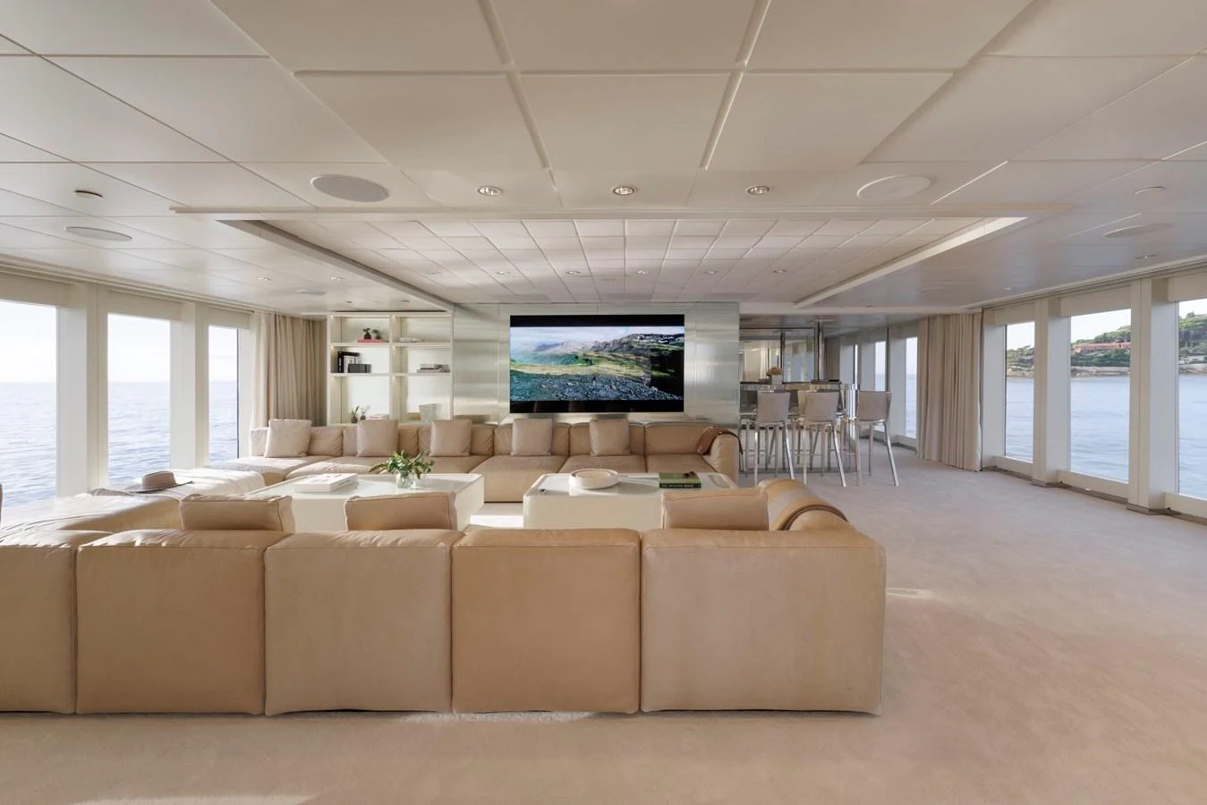 The spacious salon features plush seating, a large flat-screen TV, and panoramic windows offering stunning ocean views. aboard IDOL Yacht for Sale